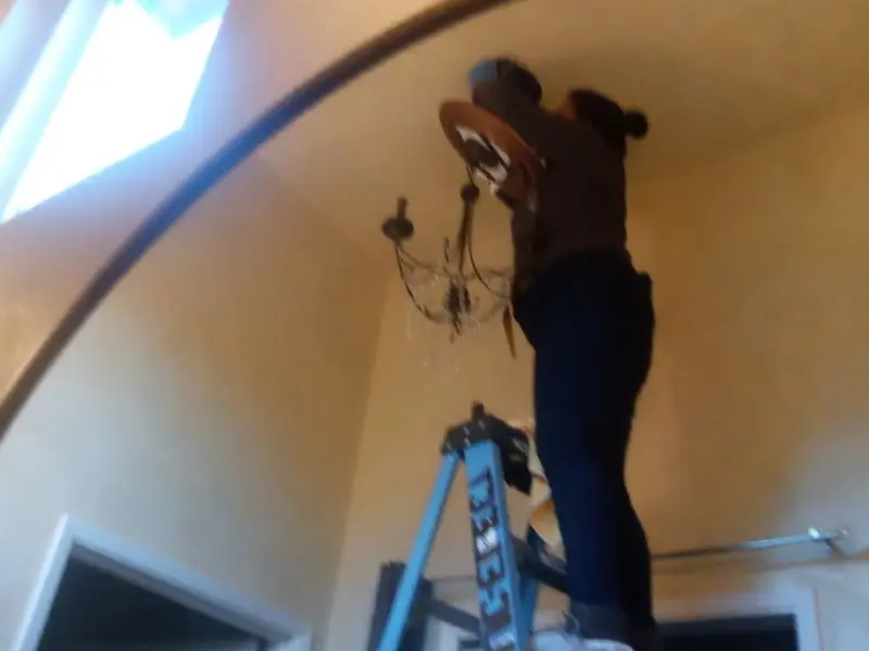 Electrician installing a chandelier in a Bluffdale residence